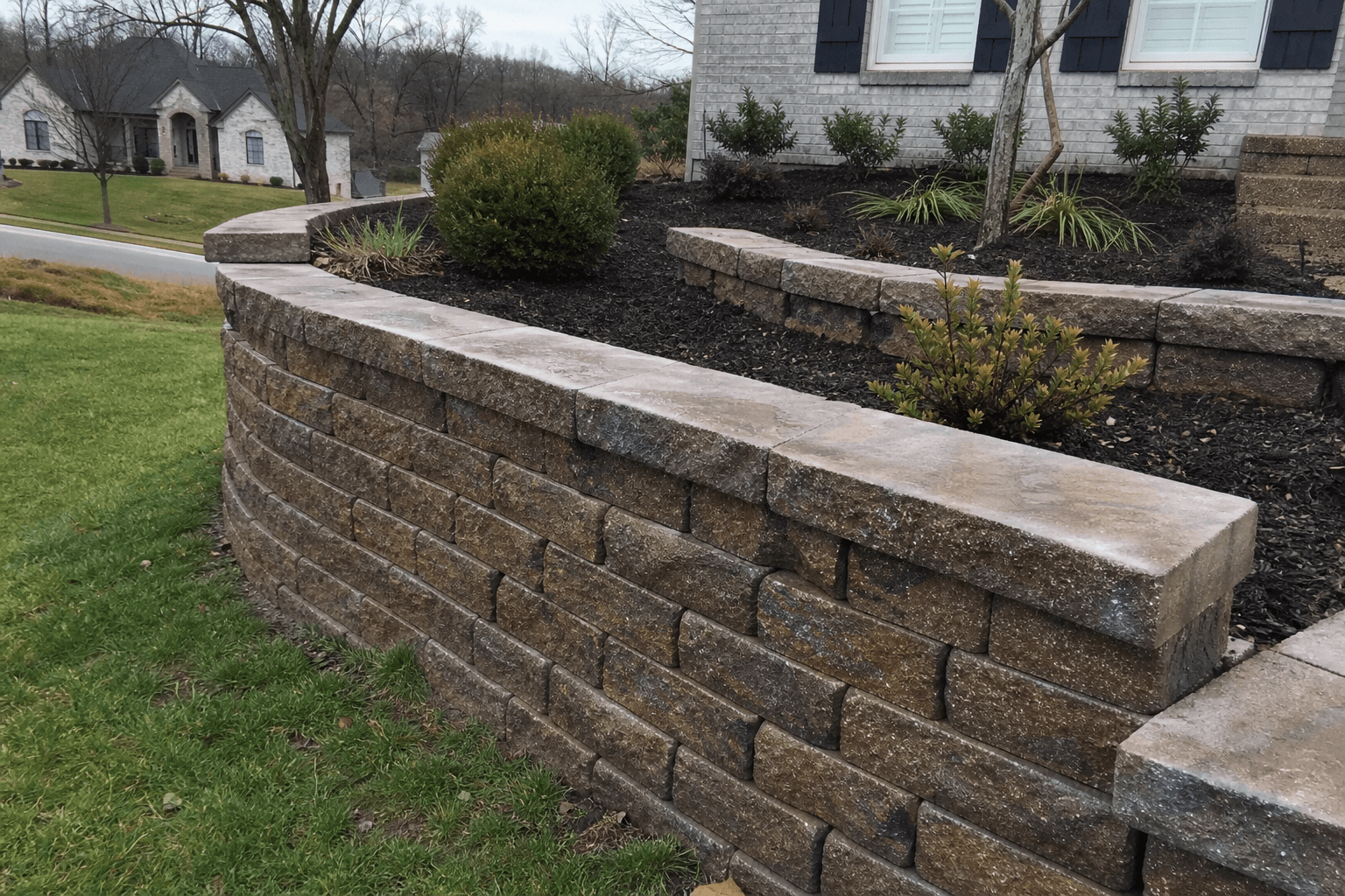 Tiered retaining wall and stone steps in front of a home.